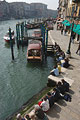 The Grand Canal and Fondamenta del Vin seen from the Rialto Bridge in Venice; buildings along the canal in the distance, and people enjoying the sunshine in the forground